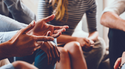 Closeup of a person's hands within a group